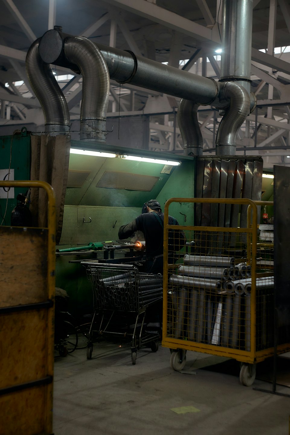 Arbeiter mit Schutzhelm schleift Metall in einer Fabrik.